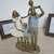 Escultura de uma família em resina, representando pais e filhos, com detalhes em dourado e camisa azul.