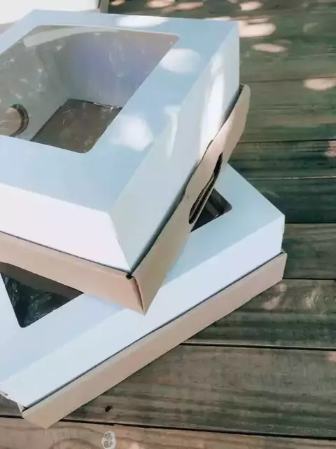 Cajas con visor de cartón blanco apiladas, mostrando la ventana transparente en la parte superior.
