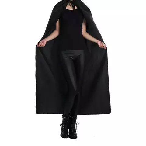 Mujer usando una capa negra sobre una camiseta negra y pantalones ajustados, con botas negras.