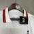 Camisa branca do AC Milan com detalhes em vermelho e preto, exibindo logo da equipe e patrocinadores.