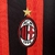 Camisa do AC Milan com listras vermelhas e pretas, logotipo da Puma e patrocínio da Emirates.