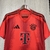 Camisa de futebol do Bayern de Munique, na cor vermelha, com detalhes em preto e logo da Adidas.