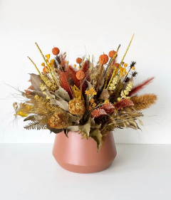 Arranjo seco com flores e folhagens em tons de amarelo, laranja e marrom em vaso de metal marrom