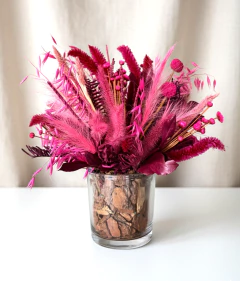 Arranjo seco em tons de rosa em vaso de vidro transparente com casca de pinus