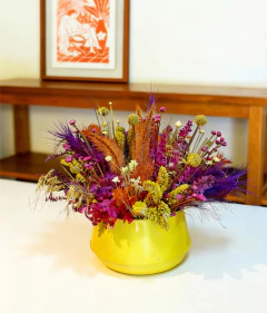 Arranjo de flores secas rosa e amarela em vaso de metal amarelo 
