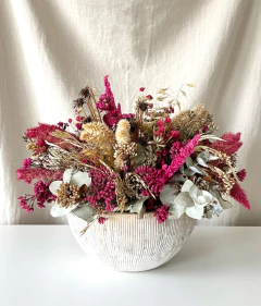 Arranjo seco de flores em vaso redondo de cerâmica branca, com flores secas em tons de rosa, bege e verde