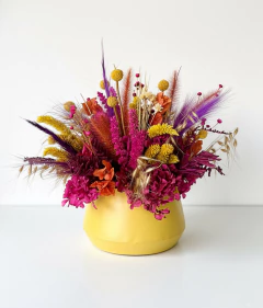 Arranjo de flores secas rosa e amarela em vaso de metal amarelo 