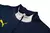 Detalhe do conjunto de treino azul da seleção de Portugal, com gola alta e zíper, apresentando o logotipo da Puma em amarelo.