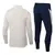Conjunto de treino da seleção de Portugal, com blusa bege de mangas longas e calça azul escura.