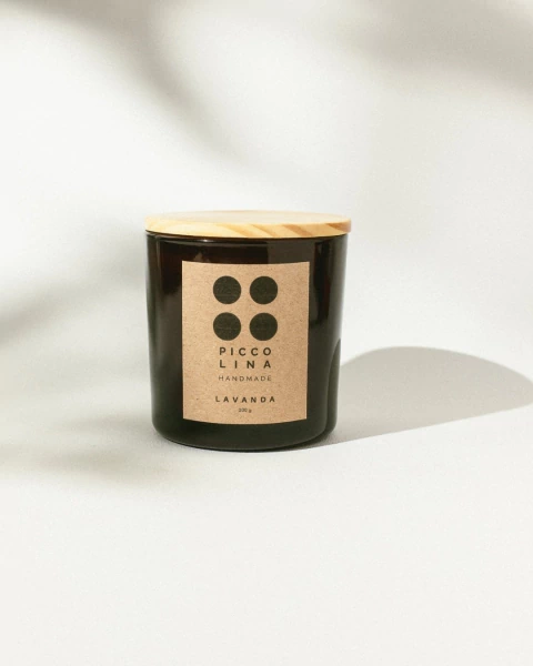 Vela aromática âmbar com tampa de madeira, rótulo em papel kraft e fragrância de lavanda, em fundo claro com sombra suave