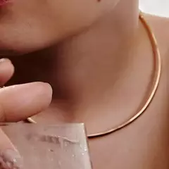 Colar choker dourado liso de aro rígido usado no pescoço de uma pessoa