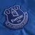 Escudo do Everton na camisa titular 2024/2025, Home I, original, oficial, azul, brasão EFC em destaque no peito esquerdo, bordado com detalhes em branco, símbolo histórico, uniforme de futebol premium.