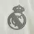 Detalhe do escudo do Real Madrid silkado em cinza na camisa de treino 2024/2025 masculina, versão jogador. Localizado no lado esquerdo do peito, combina elegância e autenticidade, reforçando a identidade merengue. Utilizada por jogadores como Vini Jr, Bel