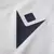 Logo da Macron na camisa reserva Away II masculina do Osasuna 2024/2025, cinza e branca. O logo é visível no peito, com detalhes precisos que complementam o design elegante e moderno.