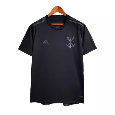 Imagem da terceira camisa do Flamengo 2023/2024 preta, modelo III, com design iridescente e aplicações furta-cor. A frente exibe o escudo do remo, logo da Adidas, listras nos ombros, e a frase “Uma vez Flamengo. Sempre Flamengo”. Jogadores como Gabigol, A
