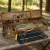 Kit para 6 personas con copas, cubiertos de madera y acero, parrilla integrada y accesorios para fogón en estuche de madera colocado sobre mesa rústica en exterior