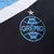 Detalhe do escudo da camisa masculina do Grêmio, modelo III 24/25, nas cores preto e azul, com estrela acima do emblema.