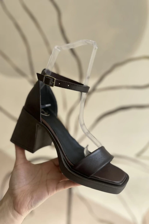 Sandalia color chocolate con taco medio y pulsera con hebilla al tobillo, diseño minimalista.