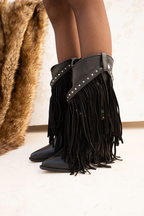 Botas negras de cuero con flecos desmontables y tachas plateadas, caña media, usadas con medias negras