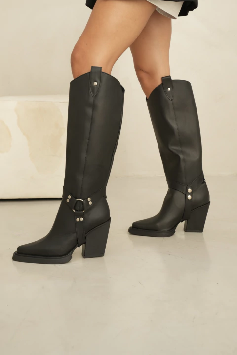 Bota texana negra de cuero con caña desmontable y detalle de hebillas metálicas.