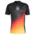 Camiseta Prepartido Alemania 24/25: Vista frontal. Diseño negro con rombos en amarillo, naranja y rojo. Escudo central de la DFB y logos de Adidas en las mangas. Estilo único para la Eurocopa 2024.