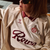 A person wearing the Köln Retrô 2025 jersey in cream and burgundy, featuring the Hummel logo and a collar design.