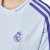 Close-up of the Real Madrid 2025 jersey featuring the club logo and striped design in white and purple.