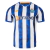 FC Porto Home Jersey 24/25: Front view. Stylized blue and white stripes with smoke graphic. Blue and white collar. FC Porto crest on the left chest, New Balance logo on the right chest.