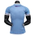 Back view of the Uruguayan national football team's home jersey for the 2023/2024 season, featuring a light blue design with purple stripes on the sleeves.