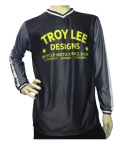 Jersey Troy Lee Designs negro con mangas grises y detalles en amarillo. Estilo retro con materiales ligeros y transpirables