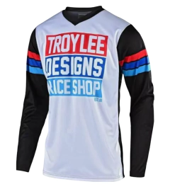 Jersey Troy Lee Designs Race Shop blanco con mangas negra y franjas celestes, ideal para motocross y BMX.