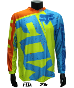 Jersey FOX verde con naranja y azul, diseño salpicado frontal y logo FOX azul claro sobre el pecho