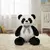 Oso panda de peluche gigante de 100 cm con moño gris, sentado sobre una alfombra en una habitación infantil. Peluche suave y de gran tamaño, ideal para regalar.