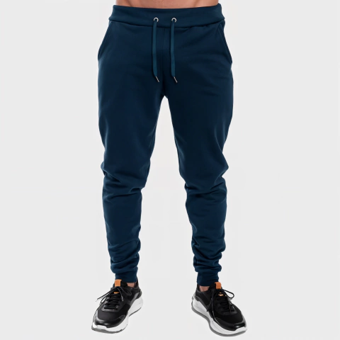 Calça moletom masculina azul marinho lisa com cadarço na cintura e punhos ajustados, usada com tênis pretos