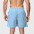 Shorts masculinos azul claro de tactel liso, vistos de trás, com elástico na cintura e bolsos laterais.