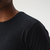 Camiseta masculina preta em malha fria, foco na parte superior do tecido e gola redonda.