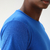 Camiseta masculina azul royal em malha fria, foco na parte superior do ombro e pescoço.