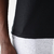 Camiseta masculina preta em malha fria, vista lateral, com detalhe da costura e parte da calça cinza.