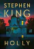 Capa do livro "Holly" de Stephen King, mostrando uma casa vitoriana iluminada ao entardecer.