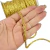 Fio trançado metalizado dourado de 5mm, com rolo visível ao fundo.