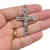 Pingente de cruz com a figura de Cristo em níquel, segurado na mão de uma pessoa.