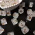 Pedrarias quadradas transparentes com detalhes em cores, ideal para artesanato