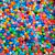 Misturinha Colors Fun 100g, uma variedade de pedrarias coloridas em diferentes formas e tamanhos.