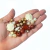 mix de miçangas em tons de dourado, marrom e creme, incluindo formatos variados