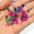 miçangas sextavadas coloridas, incluindo tons de rosa, verde, azul e laranja.