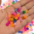 miçangas sextavadas em várias cores vibrantes, incluindo rosa, laranja, azul e verde, sobre um fundo de outras miçangas.