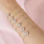 Pulseira com letrinha cravejada e flor banho de ouro 18k