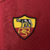 Emblema da camisa retro AS Roma 1998 Diadora na cor vinho, apresentando uma loba e os iniciais "ASR".