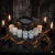Kit com 7 pós de mironga para rituais de afastamento e separação da marca 7 Folhas, organizados ao redor de um caldeirão com pó preto, decorado com velas pretas acesas, pimentas secas e cristais escuros sobre madeira escura.