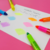 Marca texto gel retrátil em seis cores vibrantes, com amostras de tinta em um papel branco sobre fundo rosa.